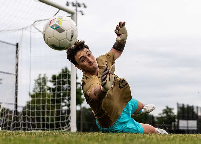 OAKVILLE, ON, Jun. 18, 2025: The Oakville SC goalkeeper dives for a save during League1 Ontario soccer action against Vaughan Azzurri at Pine Glen Park.