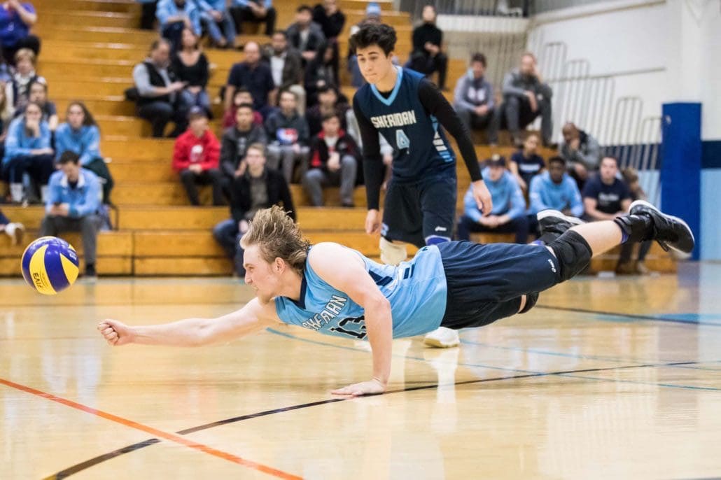 OAKVILLE, ON - NOV. 18, 2017: Liam Butchereit of the Sheridan Bruins dives for the ball in an OCAA men's volleyball game against the Humber Hawks.