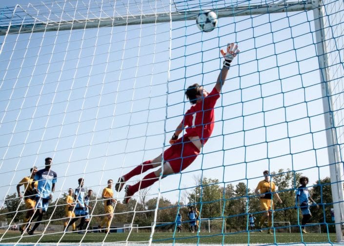 OAKVILLE, ON – SEP. 24, 2017: Dylan Roossien of the Cambrian Golden Shield fails to stop a free kick from Emilio Estevez of the Sheridan Bruins. OAKVILLE, ON - SEP. 24, 2017: Dylan Roossien of the Cambrian Golden Shield fails to stop a free kick from Emilio Estevez of the Sheridan Bruins.