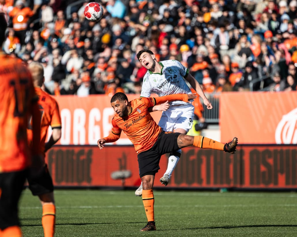 HAMILTON, ON - Apr 13, 2024: Canadian Premier League soccer game between Forge FC and Cavalry FC, Callum Montgomery (#3) Defender for Cavalry FC wins a header over Jordan Hamilton (#9) Attacker for Forge FC during the second half. (Photo by Kevin Raposo / kevinraposo.com)