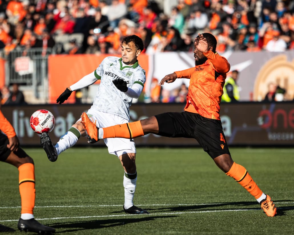 HAMILTON, ON - Apr 13, 2024: Canadian Premier League soccer game between Forge FC and Cavalry FC, Lucas Dias (#20) Midfielder for Cavalry FC and Dominic Samuel (#4) Defender for Forge FC battle for the ball during the second half. (Photo by Kevin Raposo / kevinraposo.com)